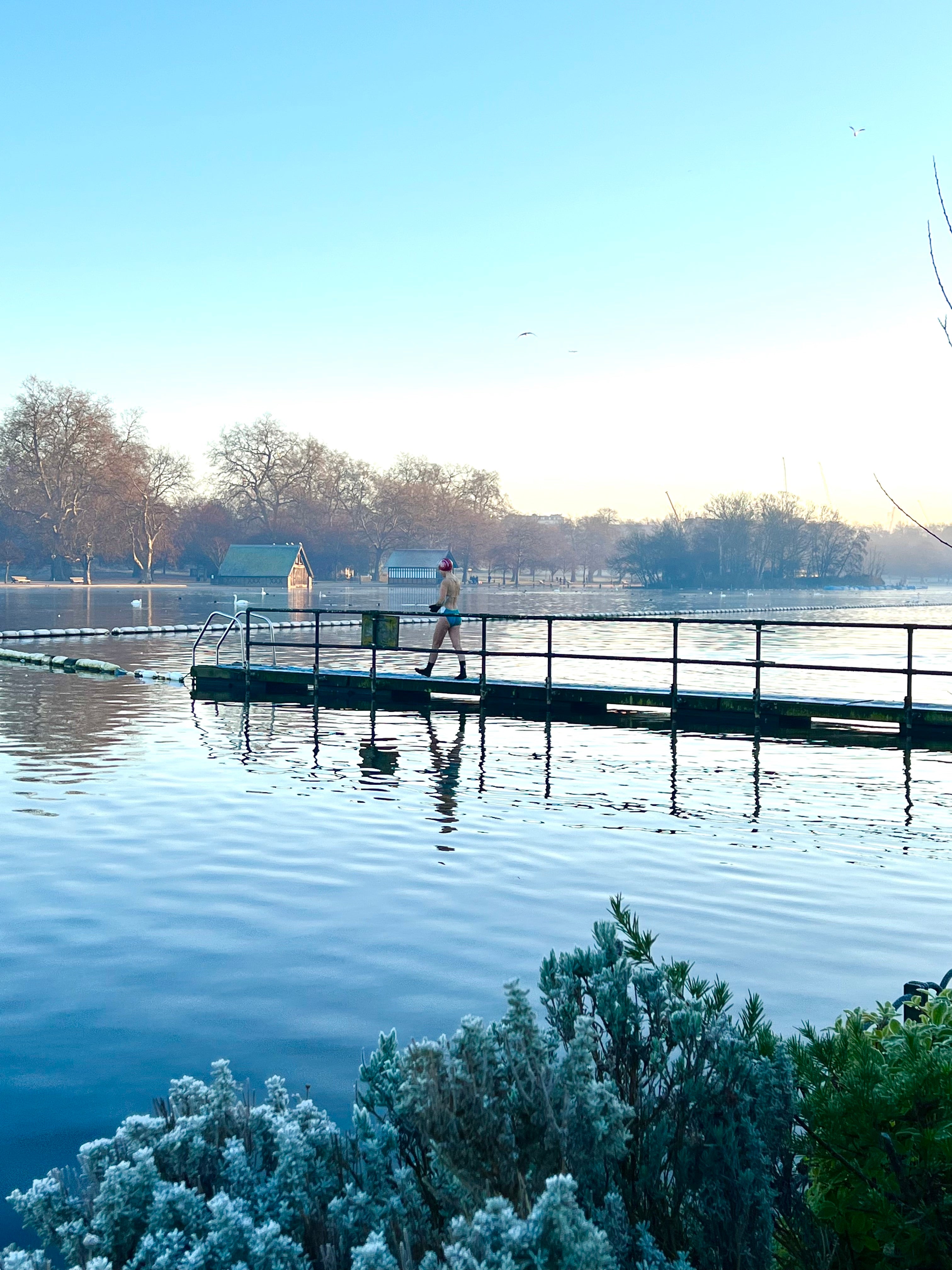 a figure walks on a frozen dock in the Serpentine in Hyde Park before swimming.